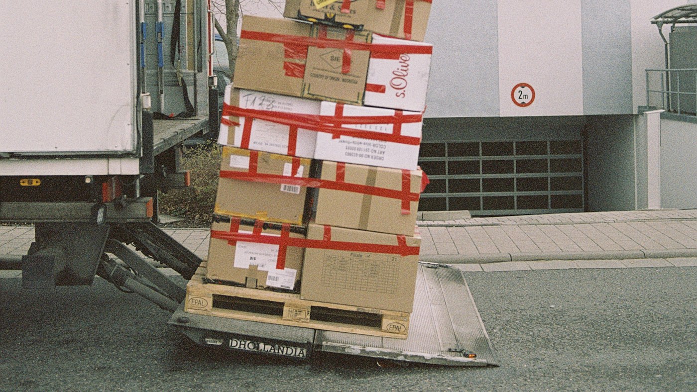 パレットに積み上げてテープで留めた段ボール箱と、トラックの昇降板